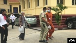 Ratt Roth Mony, wearing an orange jumpsuit and face mask, is being escorted by a national police officer after a hearing at the Supreme Court in Phnom Penh, Cambodia, July 1, 2020. (Hul Reaksmey/VOA Khmer) 