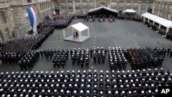 French President Francois Hollande delivers his speech, at left, during a ceremony to pay tribute to the three police officers killed in the attacks, in Paris, France, Jan. 13, 2015. 