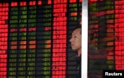 An investor stands in front of an electronic board showing stock information at a brokerage house in Shanghai, China, Sept. 2, 2015.