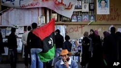 People look at photographs of people killed during the ongoing unrest in Benghazi, April 7, 2011