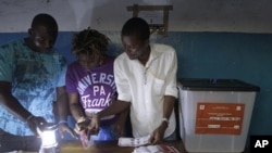 Election workers count presidential ballots by lamplight at a polling station in the West Point neighborhood of Monrovia, Liberia Tuesday, Nov. 8, 2011