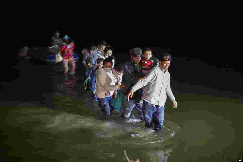 Migrant families, mostly from Central American countries, wade through shallow waters after being delivered by smugglers on small inflatable rafts on U.S. soil in Roma, Texas, March 24, 2021.