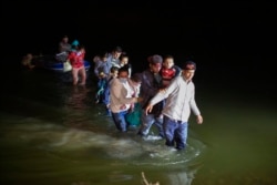 Migrant families, mostly from Central American countries, wade through shallow waters after being delivered by smugglers on small inflatable rafts on U.S. soil in Roma, Texas, Wednesday, March 24, 2021.