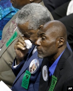 FILE - Rev. Anthony Thompson, background, husband of victim Myra Thompson, wipes his face during a memorial in Charleston, S.C., Friday, June 17, 2016 on the anniversary of the killing of nine black parishioners during a bible study.