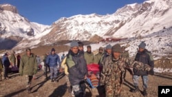 In this photo provided by the Nepalese army, soldiers carry an avalanche victim to an airlift transfer point in Thorong La pass area, Nepal, Oct. 15, 2014.
