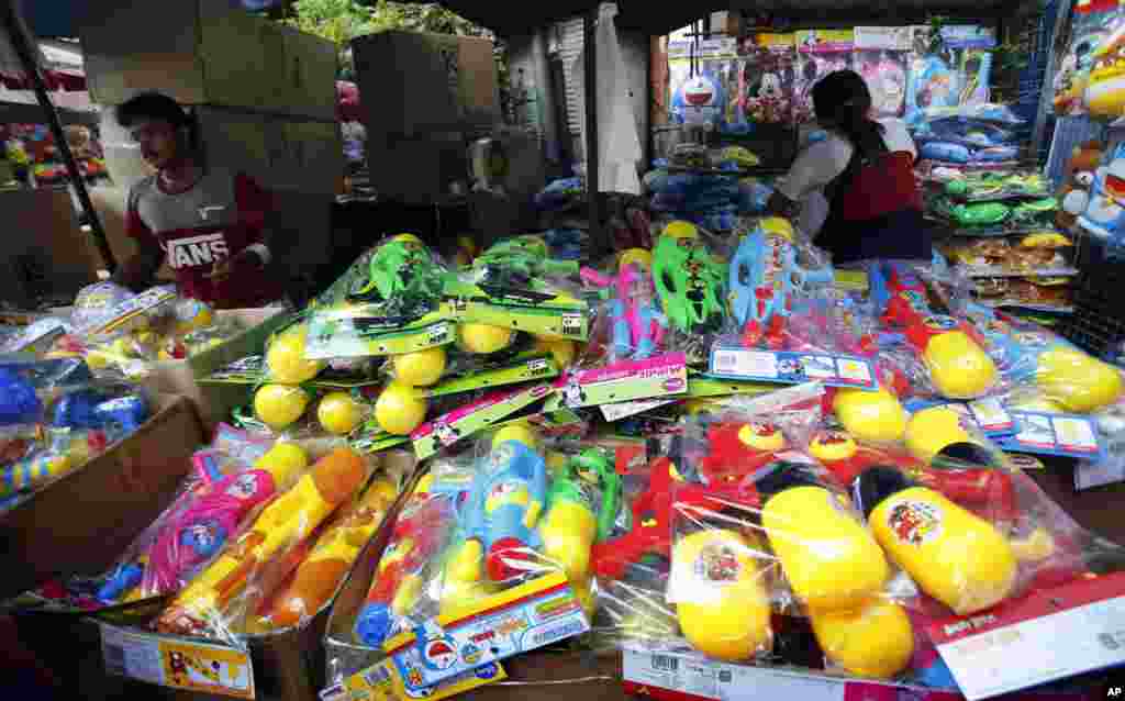 Thai vendors stand near water pistols as they wait for customers in Bangkok, Thailand, April 10, 2016.