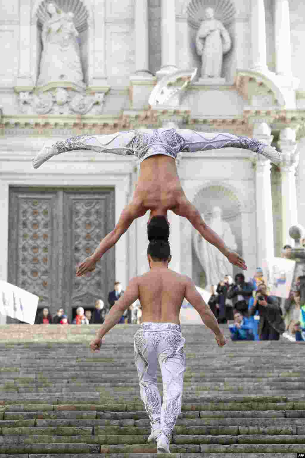 Vietnamese artist Quoc Co Giang (down) and his brother Quoc Nghiep Giang try to break the Guinness World Record by climbing stairs with one carrying the other on head to head balancing at the Cathedral of Girona, Spain.