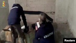 Police officers search documents in Rome in this handout video grab provided by the Italian Police on January 10, 2017.