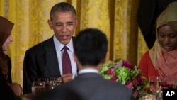 President Barack Obama sits with guests during the annual Iftar dinner, celebrating the Muslim holy month of Ramadan, in the East Room of the White House, June 22, 2015, in Washington. 