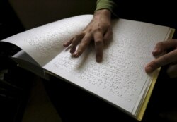 Seorang pengunjung membaca buku yang ditulis dalam huruf Braille, 15 Maret 2016. (Foto: REUTERS/Ilya Naymushin)