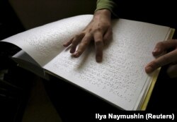 Seorang pengunjung membaca buku yang ditulis dalam huruf Braille di perpustakaan khusus untuk tuna netra, 15 Maret 2016. (Foto: REUTERS/Ilya Naymushin)