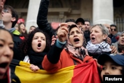 People sing as they gather around a makeshift memorial at the Place de la Bourse (Beursplein) in Brussels on March 23, 2016, a day after blasts hit the Belgian capital.