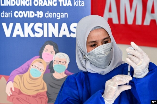 Seorang nakes mempersiapkan suntikan untuk vaksinasi COVID-19 Moderna di Barona Jaya, luar Banda Aceh, 13 Agustus 2021. (CHAIDEER MAHYUDDIN / AFP)