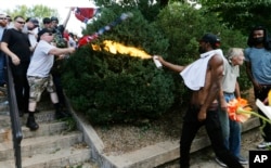 FILE - A counterprotester uses a lighted spray can against a white nationalist demonstrator at the entrance to Lee Park in Charlottesville, Va., Aug. 12, 2017.