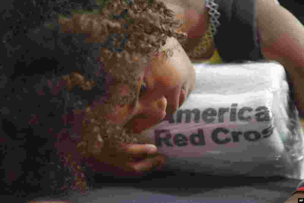 A girl rests her head on a set of towels supplied by the American Red Cross at a makeshift shelter, after arriving in San Juan, Puerto Rico, on a cruise ship with families evacuated from Caribbean islands devastated by Hurricane Irma.