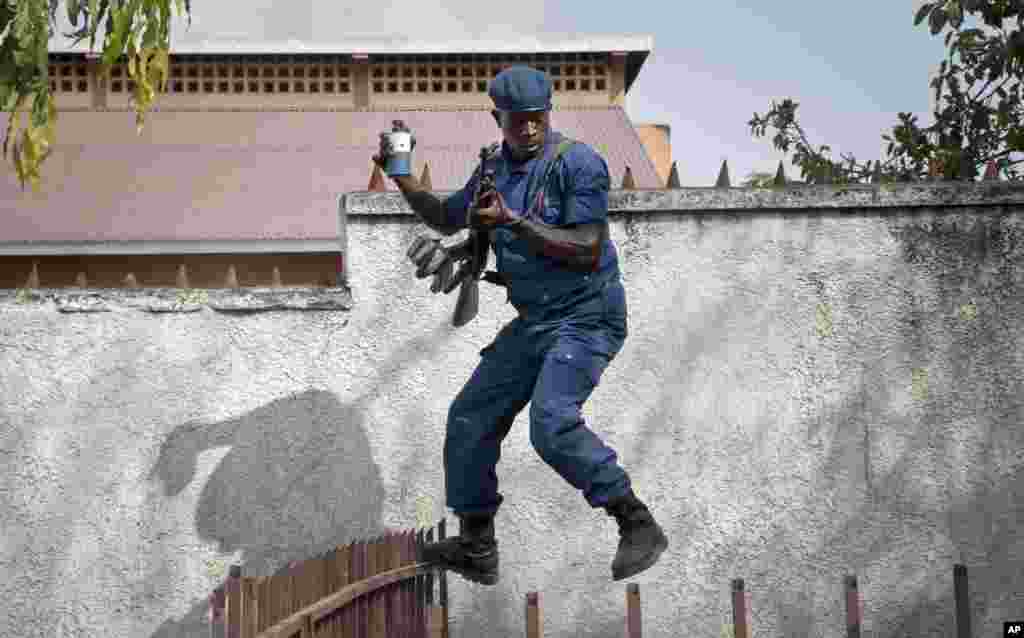 A policeman jumps as he tries to disperse angry residents in the Buyenzi area of Burundi&#39;s capital Bujumbura, after a man was killed by police and relatives were initially prevented from burying him in a timely manner in accordance with his Muslim beliefs although permission for the burial was later granted.