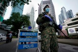 FILE - An armed soldier stands guard at a roadblock on the first day of a movement control order in downtown Kuala Lumpur, Malaysia, Wednesday, Jan. 13, 2021.