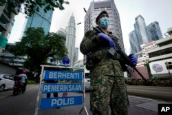 FILE - An armed soldier stands guard at a roadblock on the first day of a movement control order in downtown Kuala Lumpur, Malaysia, Wednesday, Jan. 13, 2021.