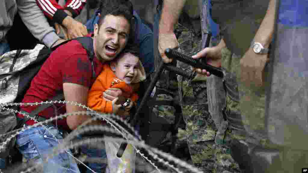 Seorang pria migran dan bayinya terjebak di tengah bentrokan antara polisi anti huru-hara Makedonia dan para migran lainnya di daerah perbatasan dekat stasiun kereta api Idomeni, Yunani utara.