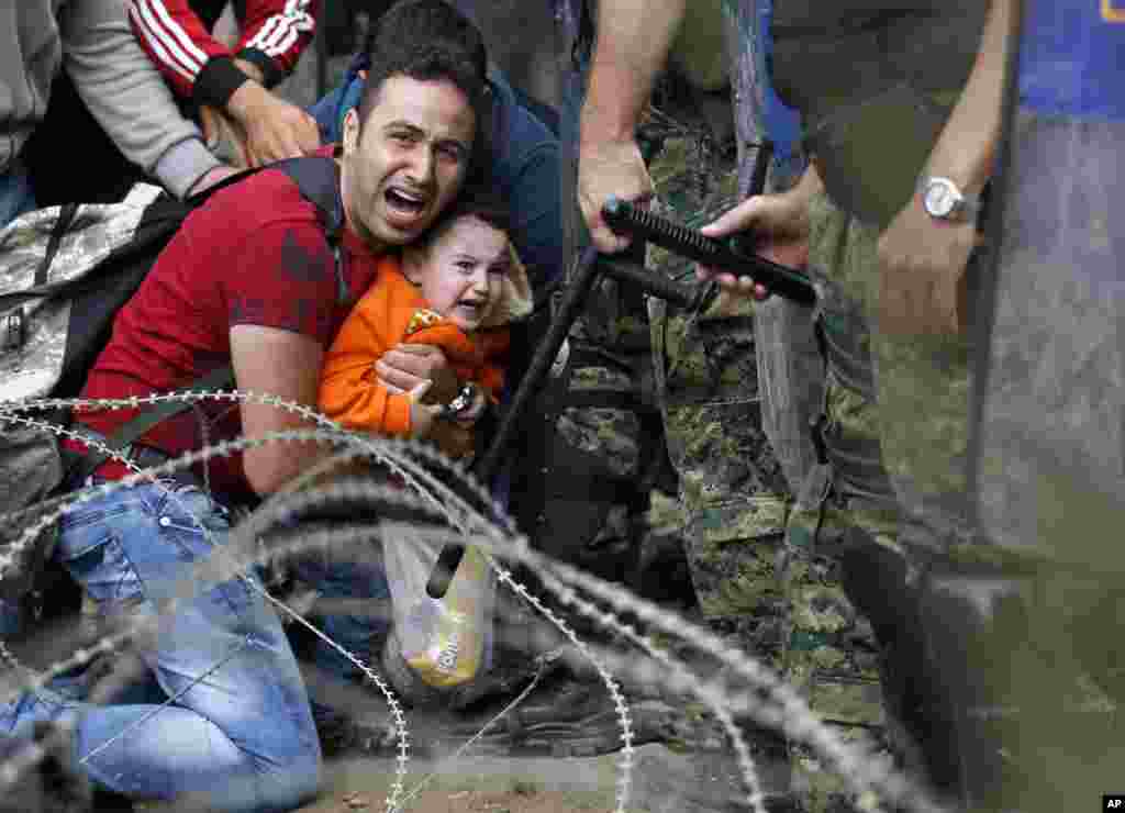 A migrant man reacts as he is caught between Macedonian riot police officers and migrants during a clash near the border train station of Idomeni, northern Greece. Macedonia declared a state of emergency on its borders Thursday to deal with a massive influx of migrants heading north to Europe.