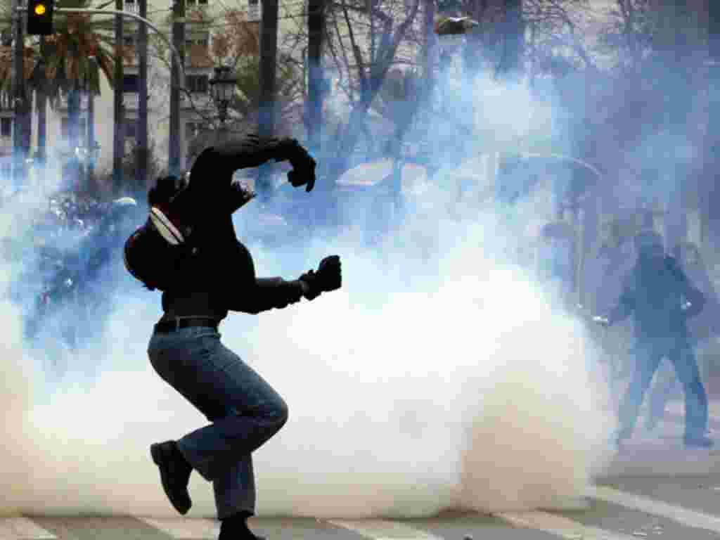 A protester throws a stone toward riot police during clashes during a two-day general strike against planned austerity measures in Athens, February 10, 2012. (AP)