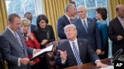 President Donald Trump looks toward Budget Director Mick Mulvaney, left, after signing an executive order in the Oval Office of the White House in Washington, March 13, 2017. 