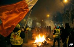 Demonstrators wearing yellow vests stands next to a burning bicycle at the Champs Elysees avenue during a protest in Paris, France, Jan. 5, 2019.