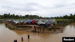 Rohingya refugees cross a stream to reach their temporary shelters at No Man’s Land between the Bangladesh-Myanmar border, at Cox’s Bazar, Bangladesh, Sept. 9, 2017.