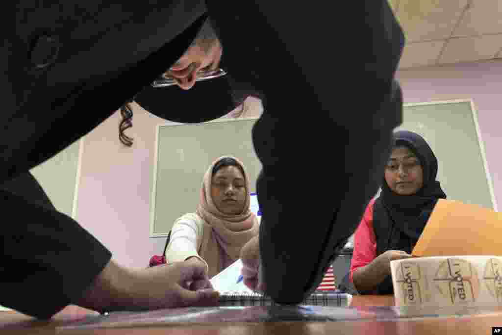 Romana Akter, left, and Urrmi Begum hand out ballot papers to an orthodox jewish man registering to cast his vote on Nov. 6, 2018, in Brooklyn borough of New York.