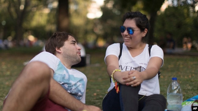 FILE - Tomas Ruiz talks with his friend Maria Julia Zuccotti as they hang out with friends at Las Heras Park in Buenos Aires, Argentina, April 2, 2019, two days before he flew to Ireland in search of work.