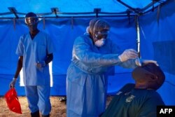 FILE - A member of South Sudanese Ministry of Health's Rapid Response Team takes a sample from a man who has recently been in contact with a confirmed case of the COVID-19 coronavirus in Juba, South Sudan, April 13, 2020.