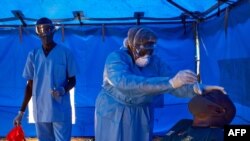  A member of South Sudanese Ministry of Health's Rapid Response Team take a sample from a man who has recently been in contact with a confirmed case of the COVID-19 coronavirus in Juba, South Sudan on April 13, 2020.