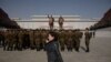 FILE - A woman talks on a mobile phone as Korean People's Army soldiers gather for a memorial tribute before the statues of late North Korean leaders Kim Il Sung and Kim Jong Il, on Mansu hill in Pyongyang, North Korea, April 15, 2019. 