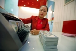 FILE - An employee counts U.S. dollars at a branch of HD Bank in Ho Chi Minh city, Vietnam, Jan. 12, 2018.