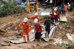 Members of a Myanmar rescue team carry a body at a landslide-hit area in Paung township, Mon State, Aug. 10, 2019.