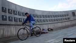 Mladić vozi bicikl pored memorijalnog obeležja žrtvama masakra u Račku 1999. (Foto: REUTERS/Hazir Reka)