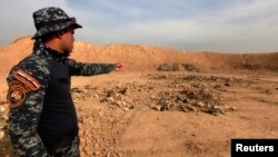 A member of Iraqi security forces gestures toward a mass grave in the town of Hammam al-Alil, which was seized from Islamic State, Nov. 9, 2016.