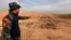 A member of Iraqi security forces gestures toward a mass grave in the town of Hammam al-Alil, which was seized from Islamic State, Nov. 9, 2016.