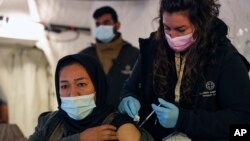 A migrant receives a booster Johnson and Johnson vaccine against COVID-19 at Karatepe refugee camp, on the northeastern Aegean island of Lesbos, Greece, Dec. 15, 2021.