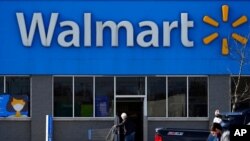 FILE - A woman pushes a shopping cart to enter a Walmart in Rolling Meadows, Ill., Nov. 5, 2020.