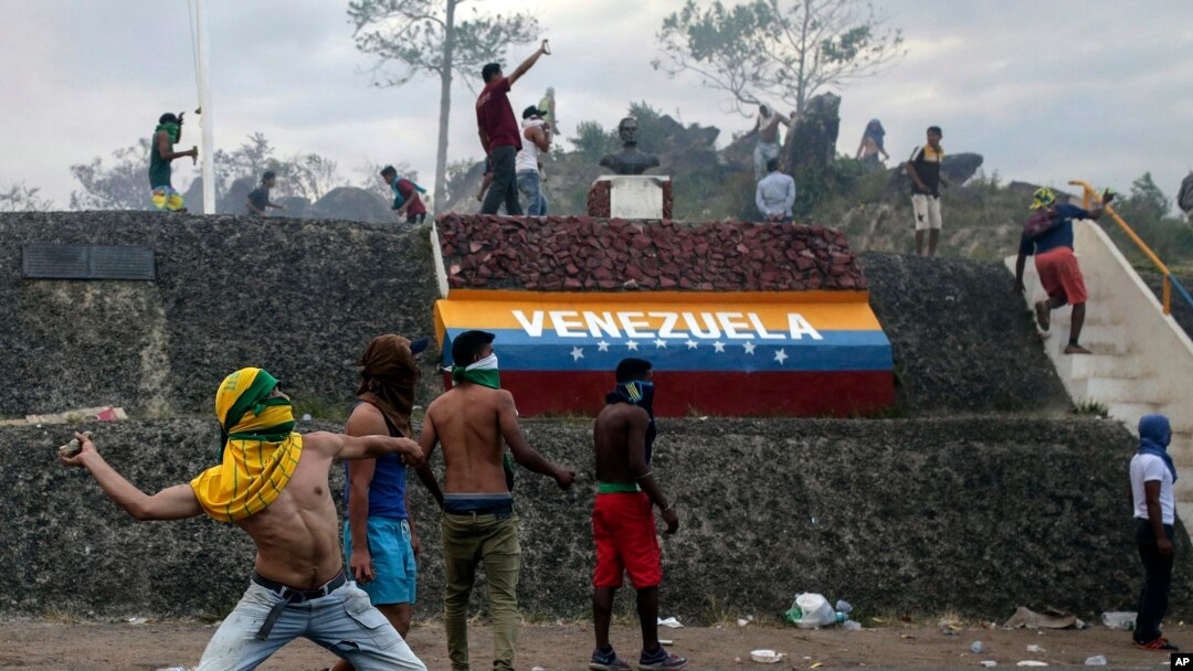 Manifestantes venezolanos lanzan piedras durante enfrentamientos con las autoridades en la frontera entre Venezuela y Brasil, el sábado 23 de febrero de 2019. Miles de personas permanecen en Pacaraima, en el cruce fronterizo internacional de la ciudad con