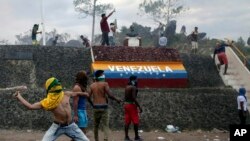 Manifestantes venezolanos lanzan piedras durante enfrentamientos con las autoridades en la frontera entre Venezuela y Brasil, el sábado 23 de febrero de 2019. Miles de personas permanecen en Pacaraima, en el cruce fronterizo internacional de la ciudad con