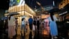 FILE - People walk under the rain with umbrellas at Taikoo Li Sanlitun in Beijing, July, 30, 2024. 