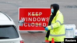 A NHS worker passes a COVID-19 test kit to a driver at a mobile test center, amid the coronavirus outbreak, in Broxbourne, Hertfordshire, Britain, Feb. 2, 2021. 