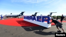 FILE - Workers set up at an Embraer display area prior to the opening of the National Business Aviation Association (NBAA) exhibition in Las Vegas, Nevada, Oct. 21, 2019.