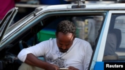 FILE - A taxi driver checks his smartphone as he waits for his customers in Addis Ababa, Ethiopia, Nov. 12, 2019.