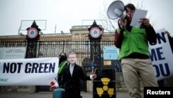FILE: A Green activist, wearing a mask depicting French President Emmanuel Macron, protests a push to include nuclear energy and natural gas in the EU Green taxonomy, in front of the Quai d'Orsay in Paris, France, Dec. 14, 2021.