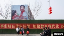 Men ride a scooter past a poster showing Chinese President Xi Jinping on the side of a school building in Henan province, China Feb. 22, 2019.