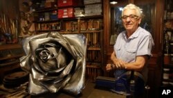 Juan Carlos Pallarols, 74, poses with a rose made with pieces of warplanes from the Falklands war, at his studio in Buenos Aires, Argentina, Jan. 25, 2017.