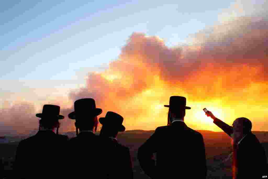 Jewish men look at a forest fire that broke out near kibbutz Beit Oren in the north of Israel December 2. The huge forest fire swept northern Israel on Thursday, killing up to 40 peopl. (Nir Elias/Reuters)